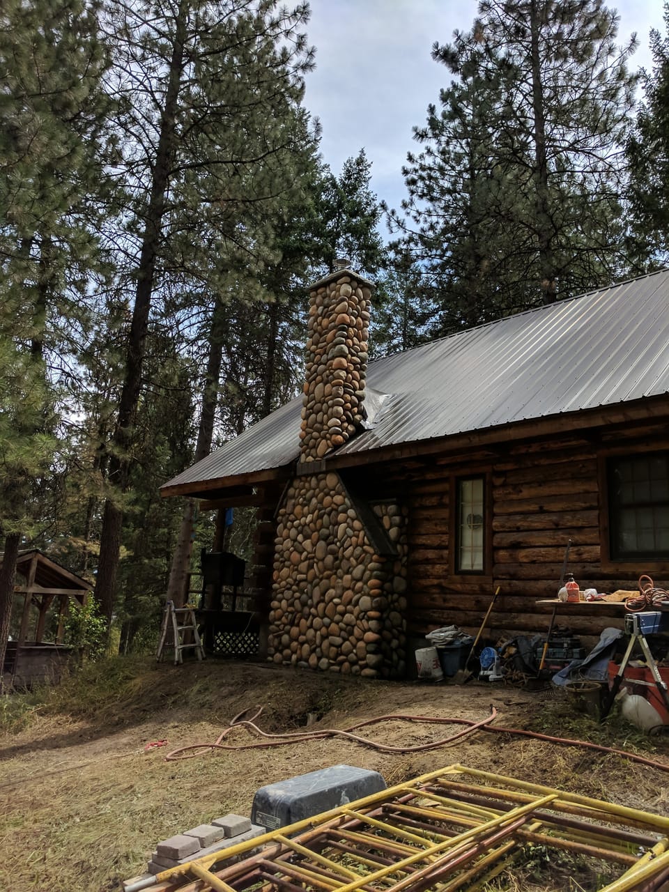Finished manufactured river rock chimney on the log cabin in the pines with the scaffold taken down