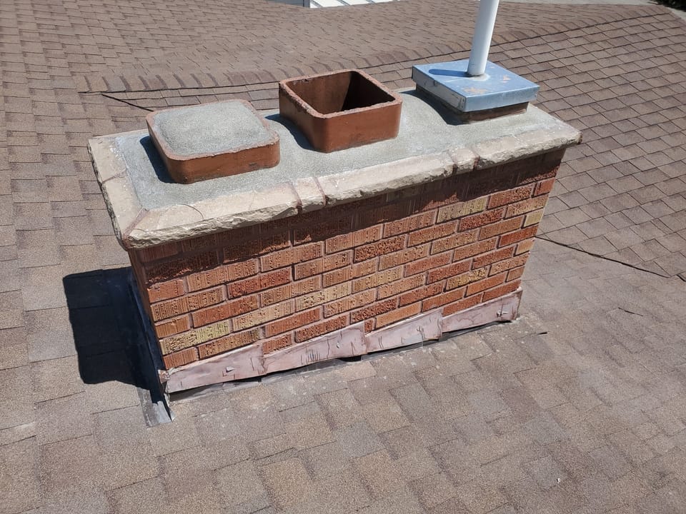 Rebuilt brick chimney with a new cast cap, clay flue tile and fresh flashing at the roofline