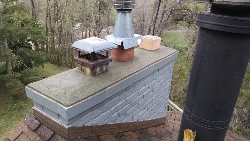 Rebuilt chimney with new concrete cap, drip edge and new top liner section above a shingled roof