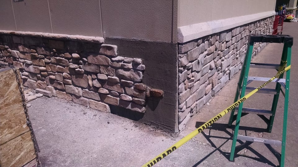Building corner stripped back to the mortar scratch coat with new lighter stone set on the return