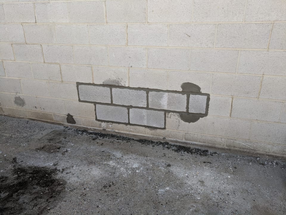 New concrete blocks laid into the opening with fresh mortar joints, not yet painted