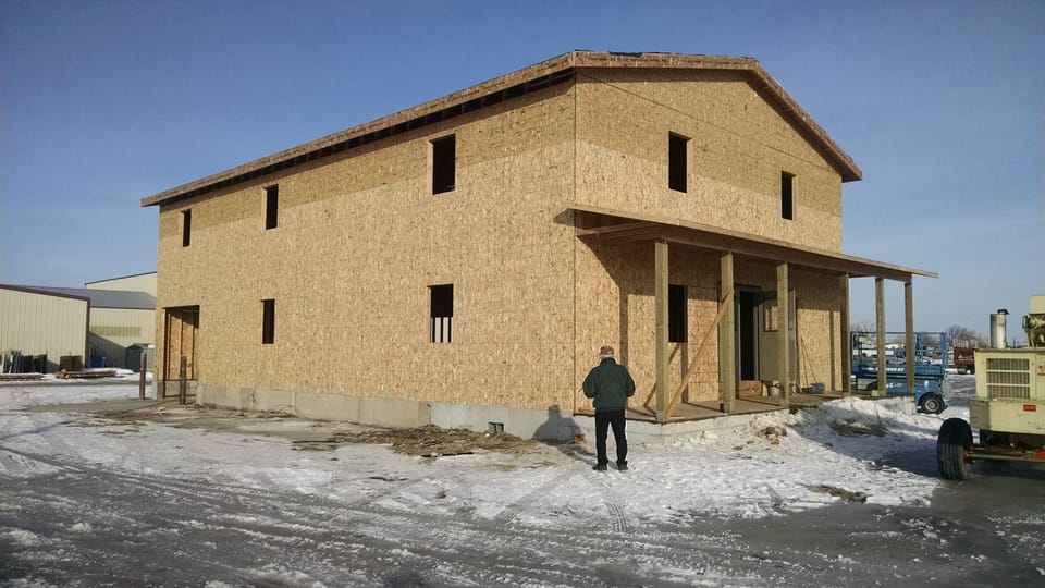 Bare sheathed two-story commercial building on a concrete stem wall with snow on the ground