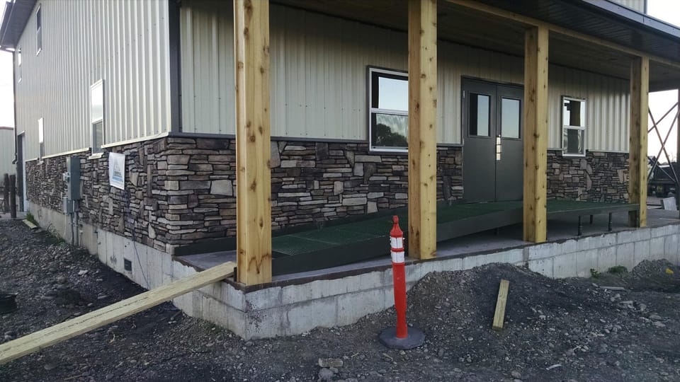 Finished stone veneer wainscot along the covered entry of the new commercial metal building