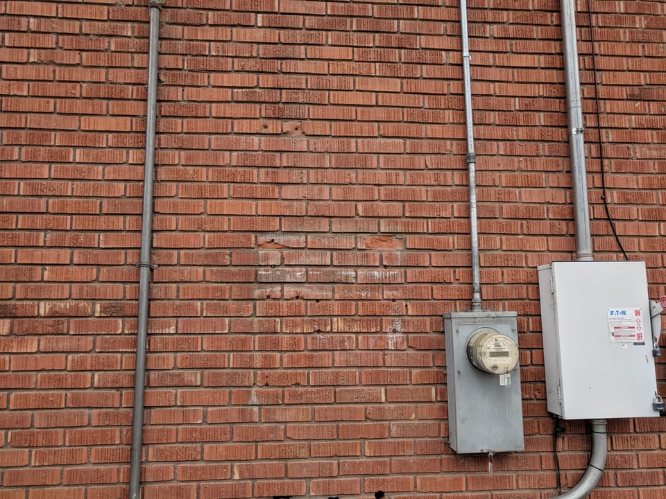 Repaired brick wall at the Meridian Masonic Temple with replacement bricks set in around the electrical meter
