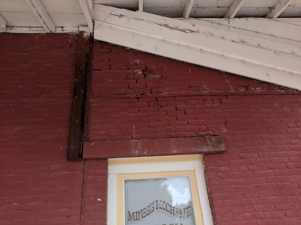 Deteriorated brick and open mortar joints below the eave beside the saloon window, Idaho City