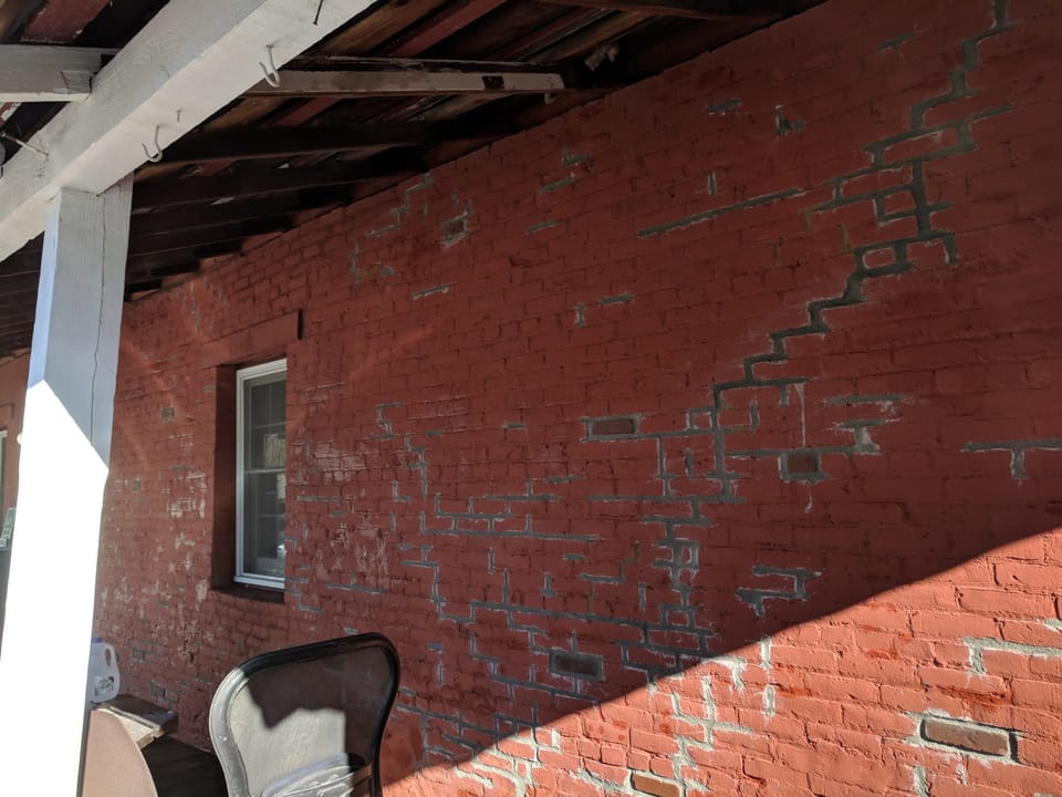 Brick wall fully repointed with fresh grey mortar joints before painting, Miners Exchange, Idaho City
