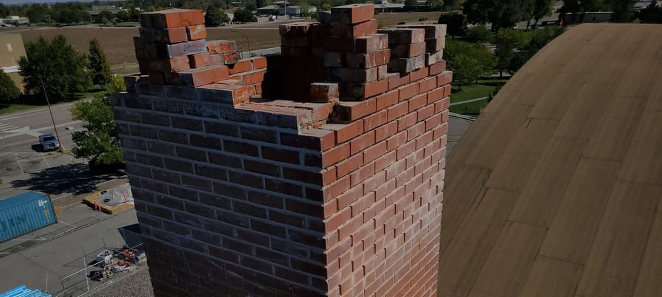 Top of the brick chimney partly taken down and rebuilt course by course above the hangar roof