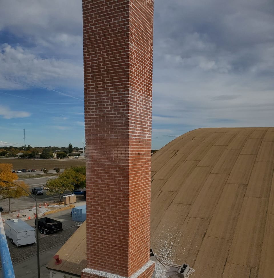 Repointed brick chimney shaft with fresh mortar where it meets the hangar roof, Mountain Home