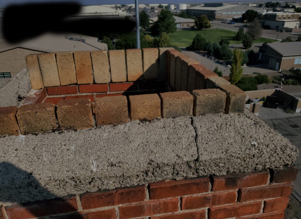 Cracked concrete wash and weathered brick on the open top of the hangar chimney
