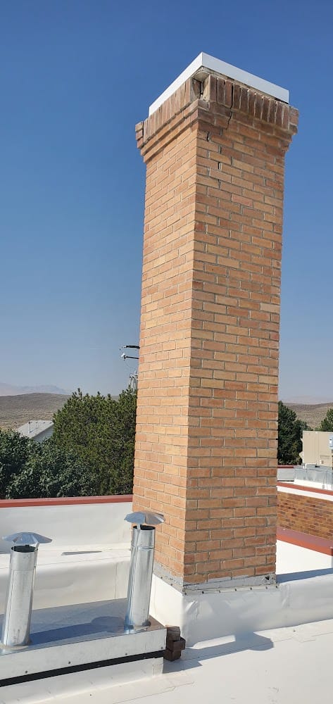 Tall brick chimney with a corbelled cap on the white flat roof of the Owyhee County Courthouse, Murphy, Idaho
