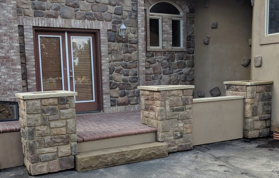 Finished patio with stone veneered planter columns, cast caps and a wide stone step to the driveway