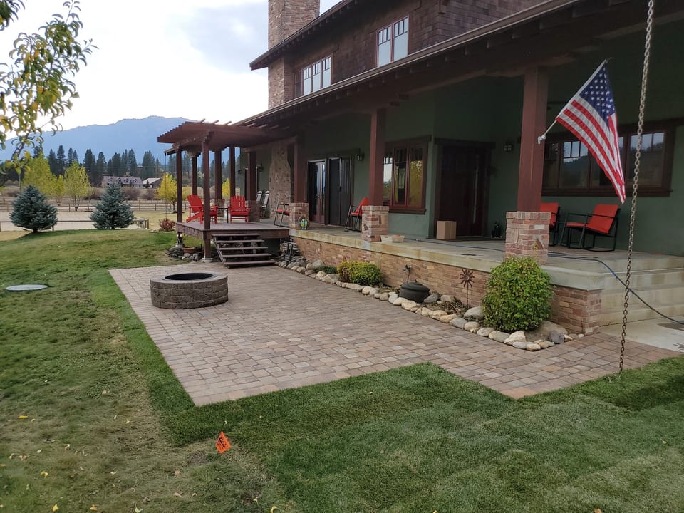 Finished paver patio with a round block fire pit running the full length of the house