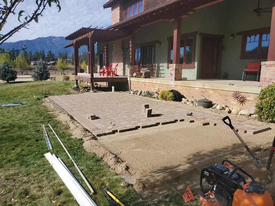 Concrete pavers being laid in running bond over screeded sand along the back of the house