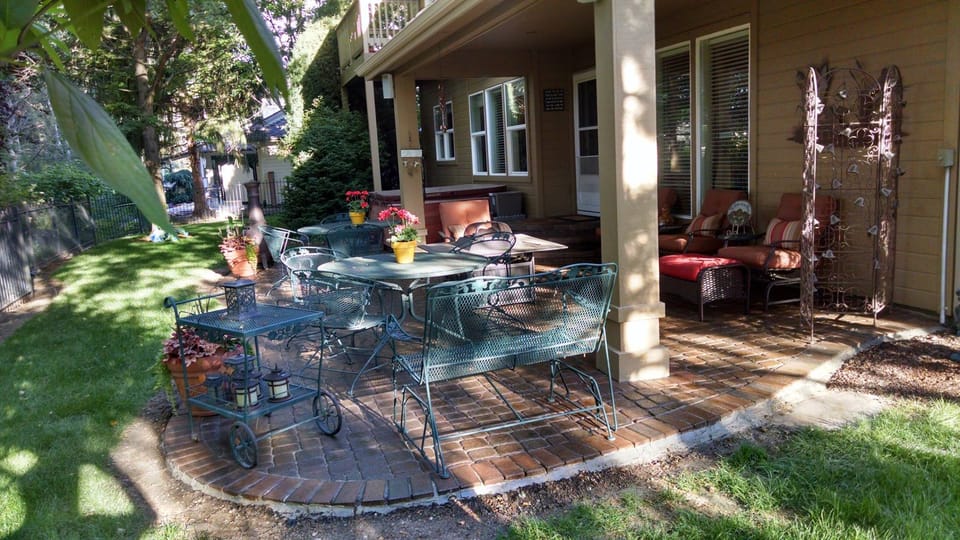 Restored and sealed paver patio with brick border and wrought iron furniture in a shaded back yard