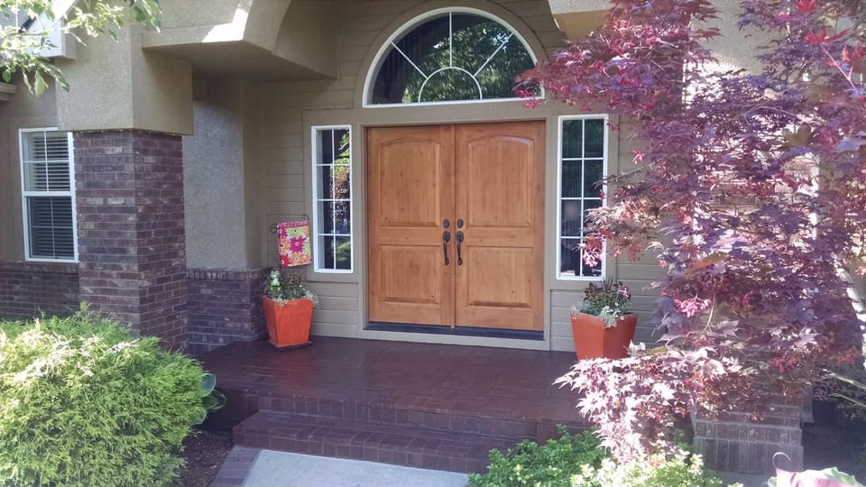 Front entry with cleaned and sealed brick porch, steps and columns below arched transom and wood double doors