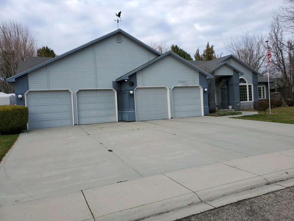 Blue-gray ranch house with four garage doors and stucco entry columns before the stone veneer went on