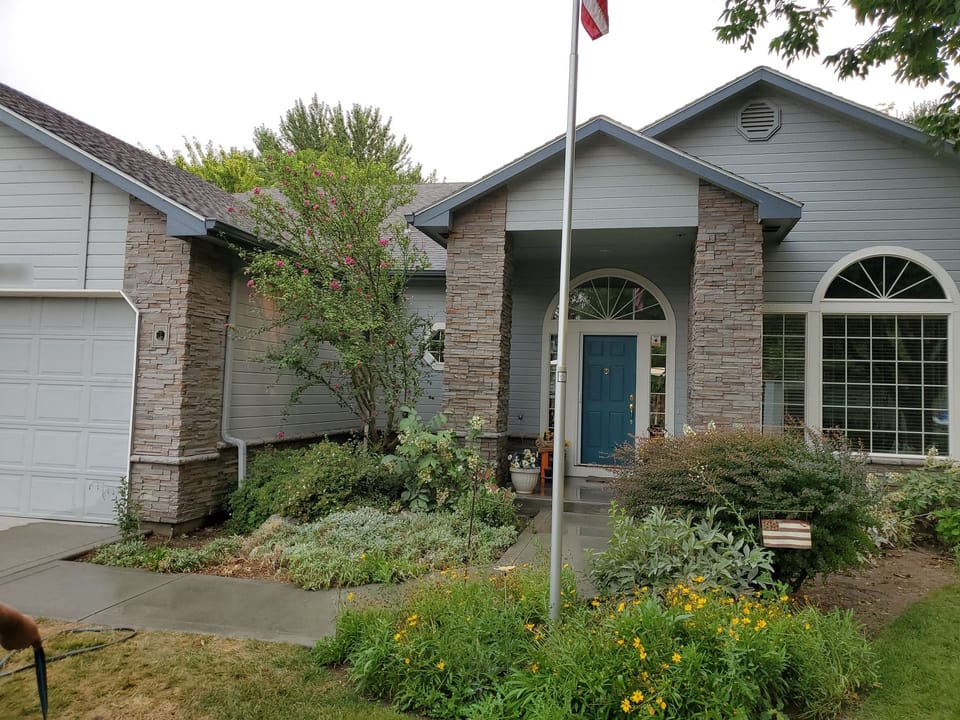 Stacked stone veneer columns flanking the arched front entry and wrapping the garage corner