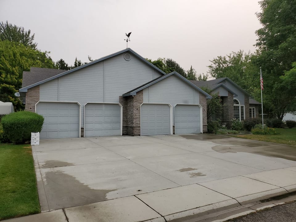 Four-door garage with new stacked stone veneer on the center pier and house corner