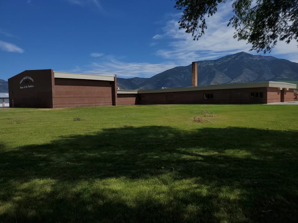 Swan Valley School after cleaning, brick facade one even color under blue sky with mountains behind