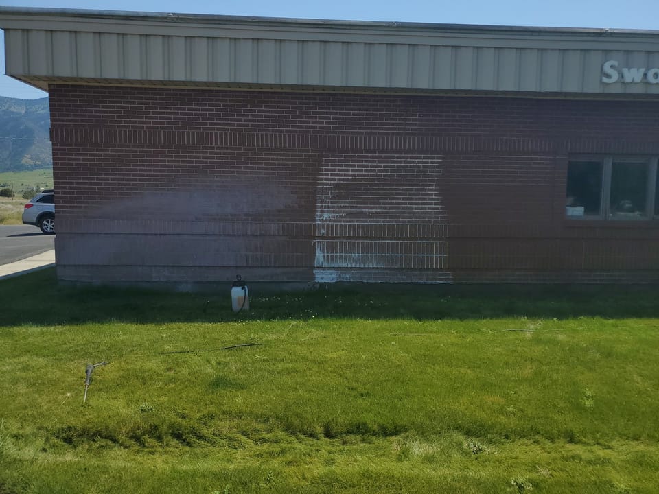 Swan Valley School brick wall part way through cleaning, a washed section beside brick still heavily stained