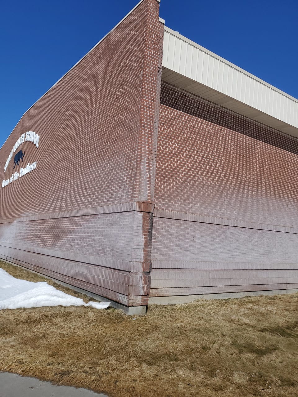 Corner of Swan Valley School under the Home of the Panthers logo, lower brick whitened by mineral staining