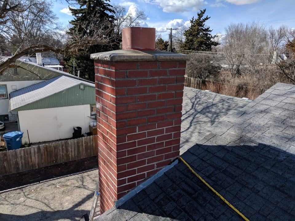 Finished brick chimney rebuild with a new concrete crown, painted flue extension and fresh flashing